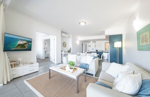 Un salon moderne avec un canapé, une table basse et un tableau représentant un paysage côtier.