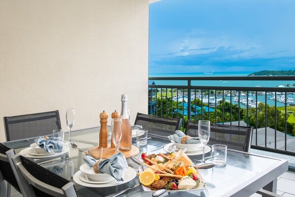 A dining table set for two with a view of a marina and boats.