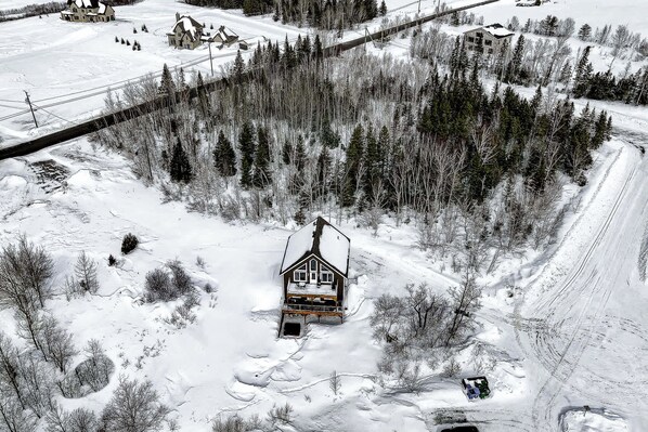 A snow-covered landscape with a cabin surrounded by trees.