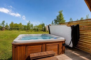 A hot tub with a wooden deck and a wooden pergola in a backyard. - Spa and River View | Le Haut-Perche (Petite-Rivière-Saint-François)