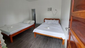 A room with two wooden beds, white bedding, a wooden door, a wall-mounted air conditioning unit, and a visible power outlet. - LAWAK BAKASYUNAN (Moalboal)