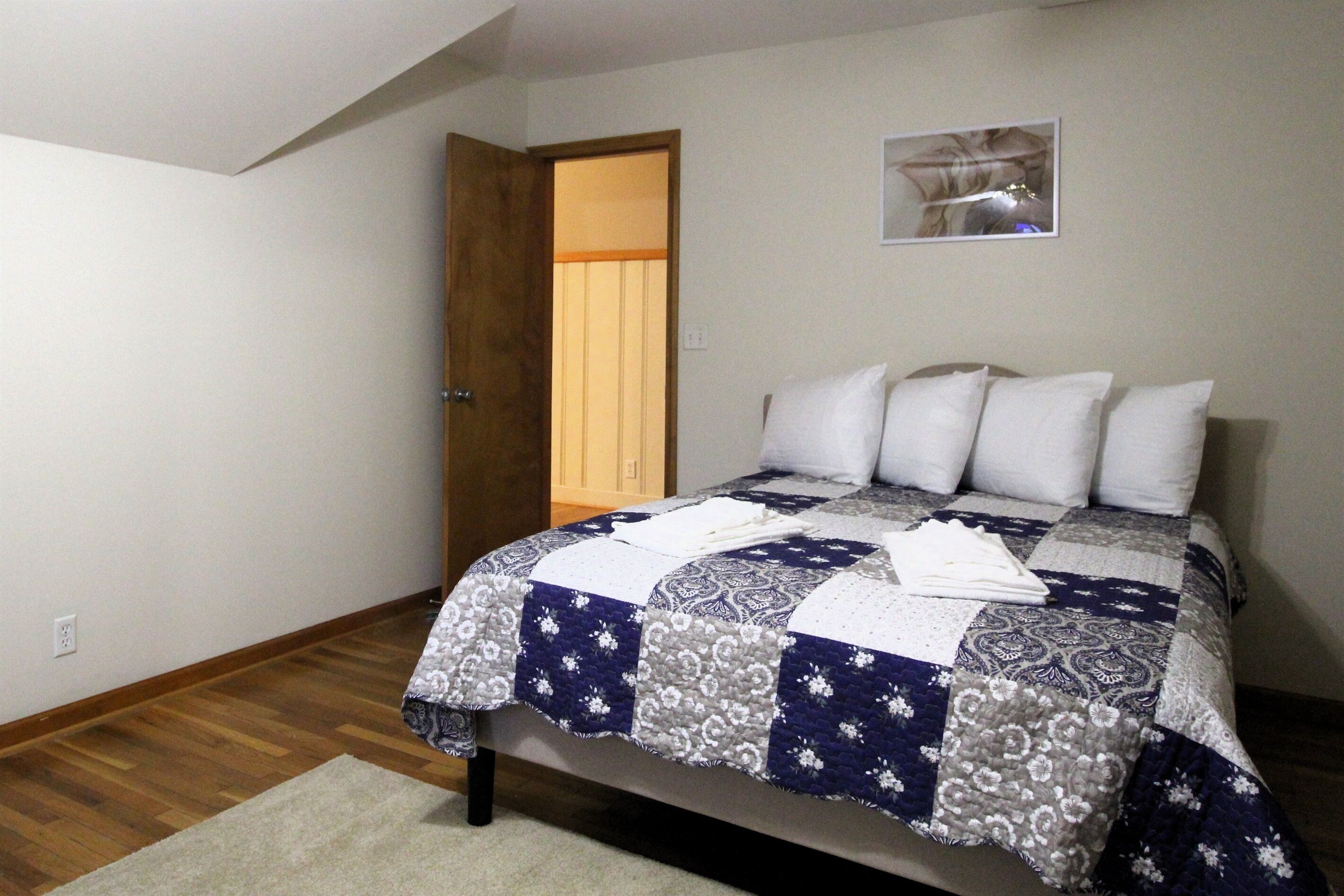 A bedroom with a bed, a door, and a wall-mounted picture.