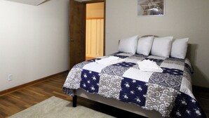 A bedroom with a bed, a door, and a wall-mounted picture. - Cooperstown Baseball Rentals - Sky Box (Oneonta)