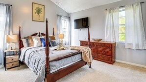 A bedroom with a four-poster bed, wooden dresser, and a flat-screen TV mounted on the wall. - Port Charlotte Home Near Beaches & Dining (Port Charlotte)