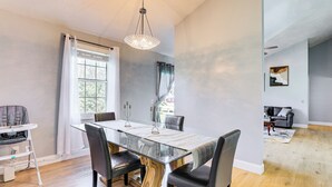 A dining area with a glass table, black chairs, a high ceiling, and a view of the living room. - Port Charlotte Home Near Beaches & Dining (Port Charlotte)