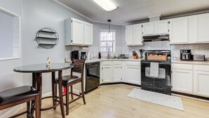 A modern kitchen with white cabinets, a black stove, and a round glass table with chairs. - Port Charlotte Home Near Beaches & Dining (Port Charlotte)