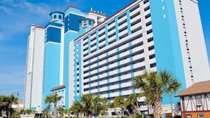 A multi-story hotel with a blue and white facade, featuring a central tower with a rounded top and smaller towers on either side.