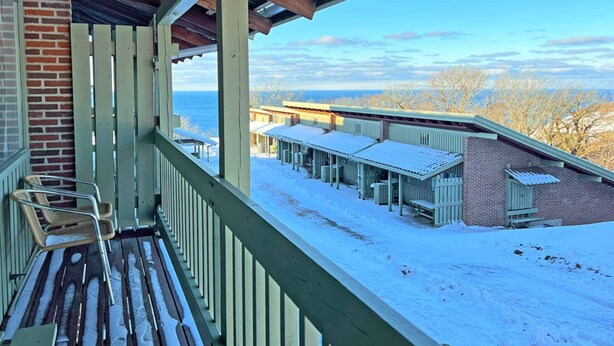 Eine überdachte Veranda mit Blick auf einen mit Schnee bedeckten Gebäudekomplex.