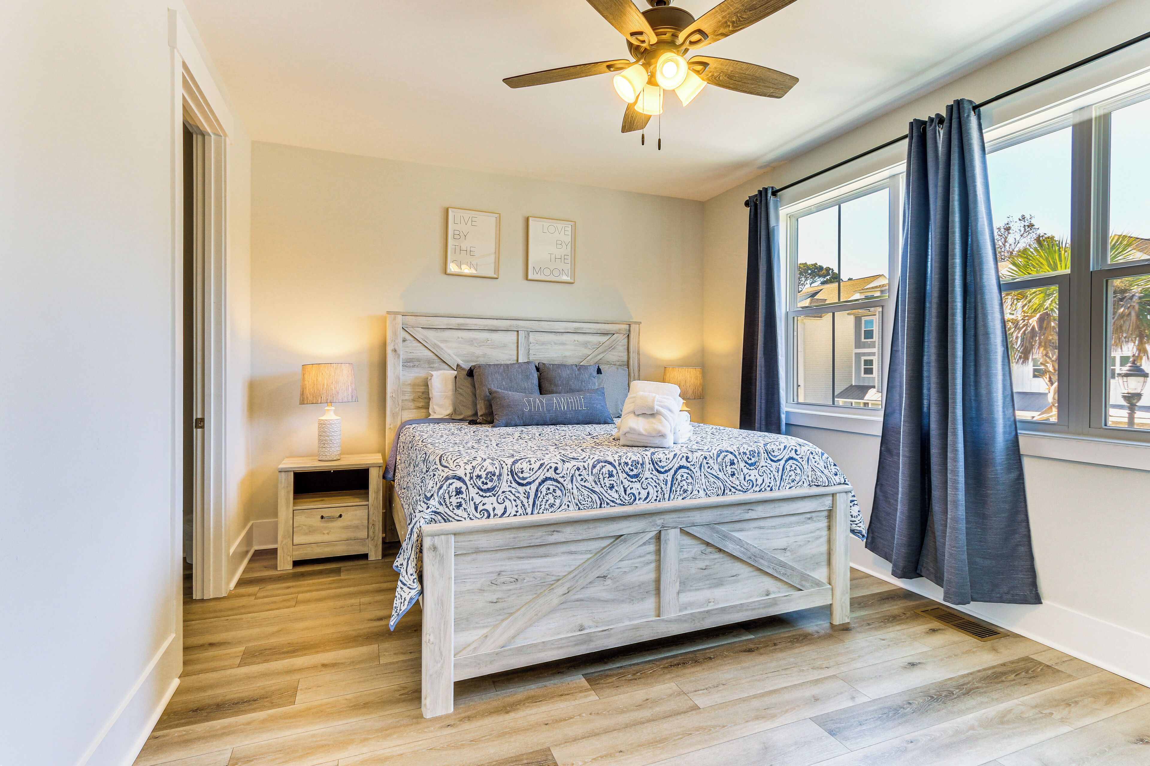 A bedroom with a wooden bed, a ceiling fan, and a window with curtains.