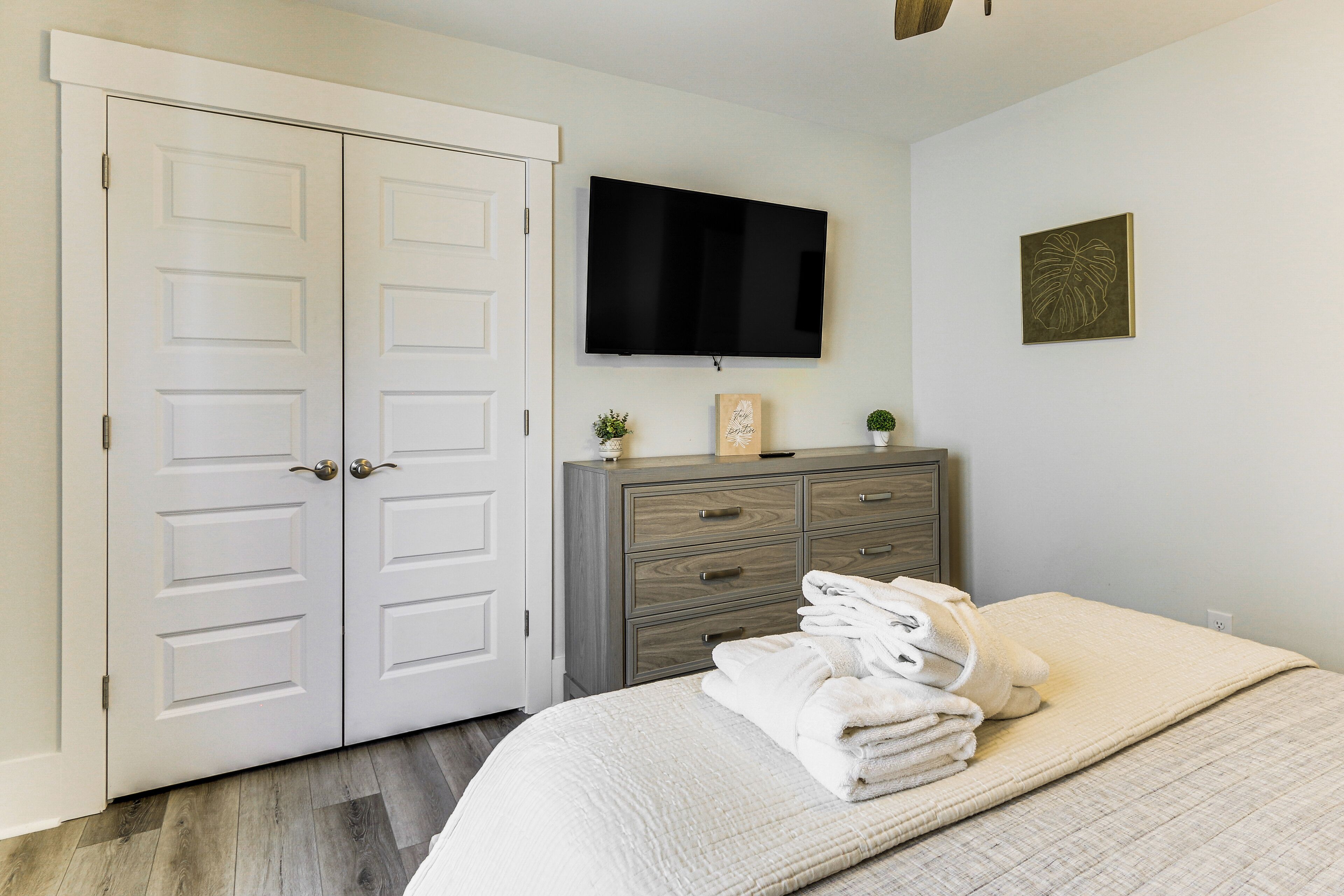 A bedroom with a bed, a dresser, a TV, and a door.