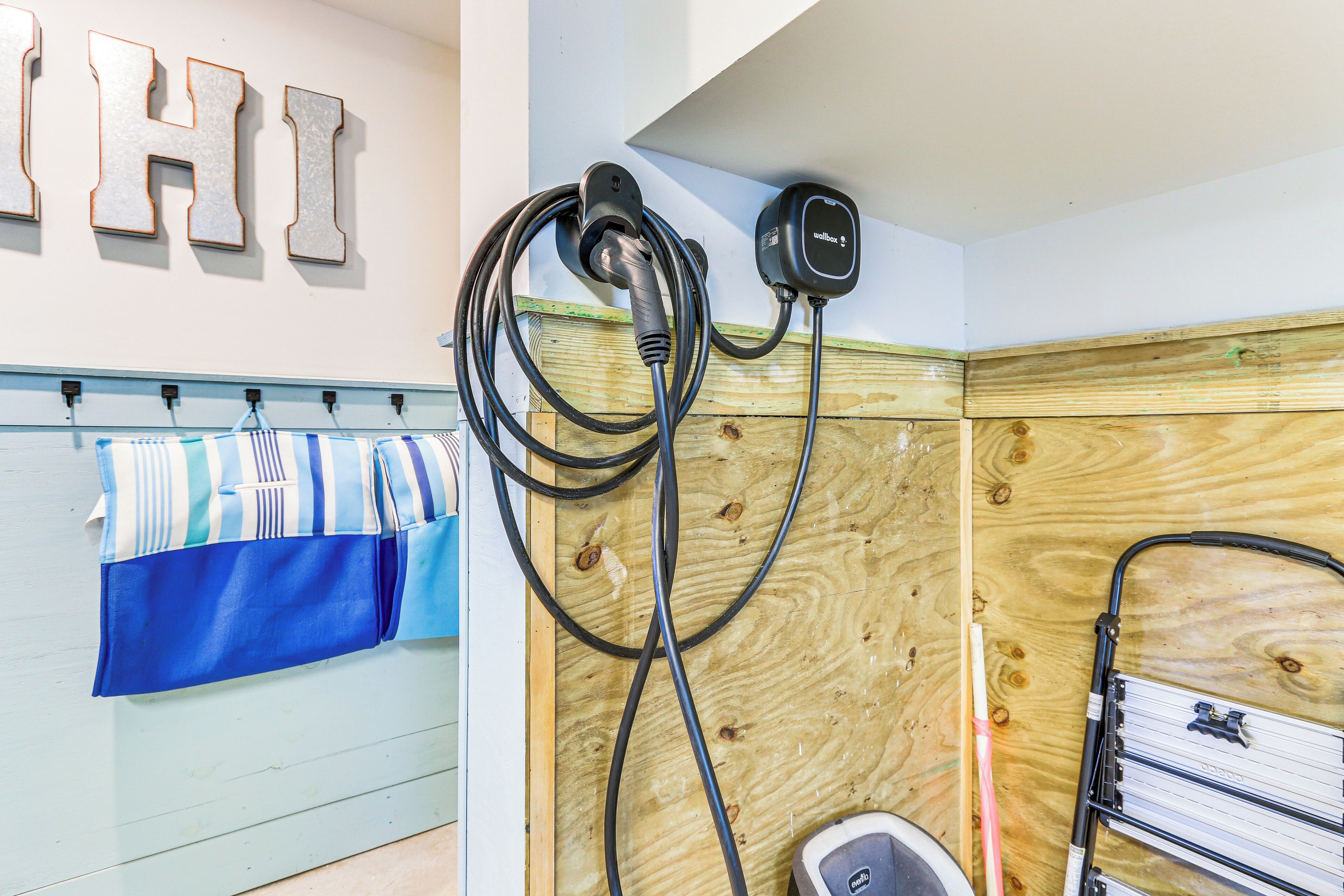 A room with a wooden wall, a towel rack with striped towels, and a black charging station.