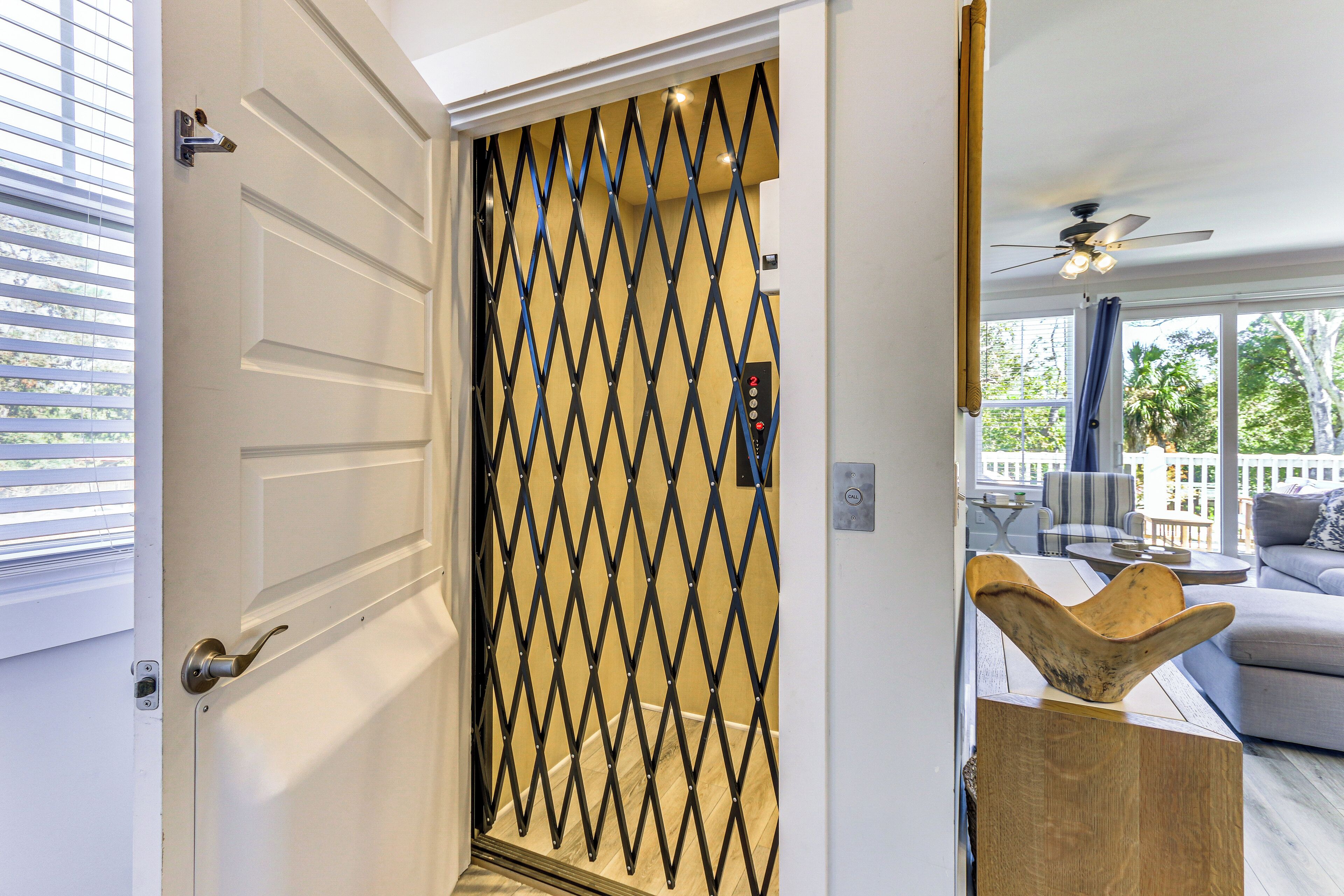 A modern interior with a white door, a diamond-patterned security gate, and a wooden bowl on a side table.