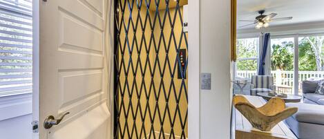A modern interior with a white door, a diamond-patterned security gate, and a wooden bowl on a side table.