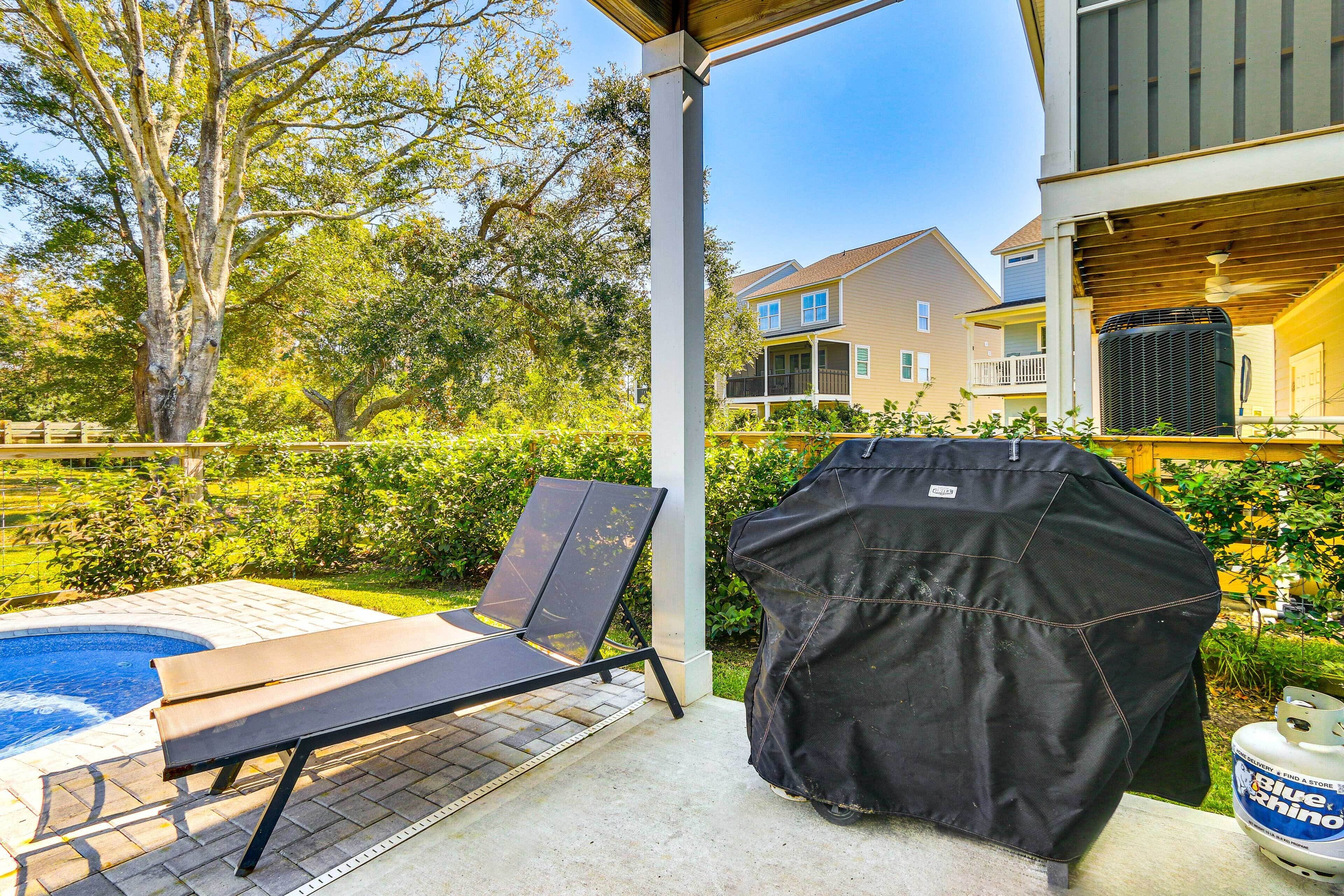 A covered outdoor area with a pool, lounge chair, barbecue grill, and a propane tank.