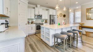 A modern kitchen with white cabinetry, stainless steel appliances, and a central island with bar stools. - 1 Mi to Beach: Family-friendly Hilton Head Retreat (Hilton Head Island)