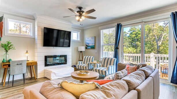 A living room with a sofa, chairs, a TV, a fireplace, and a balcony with a view of trees. - 1 Mi to Beach: Family-friendly Hilton Head Retreat (Hilton Head Island)