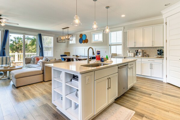 A spacious kitchen with white cabinetry, a central island with a sink, and a dining area with a sofa and table. - 1 Mi to Beach: Family-friendly Hilton Head Retreat (Hilton Head Island)