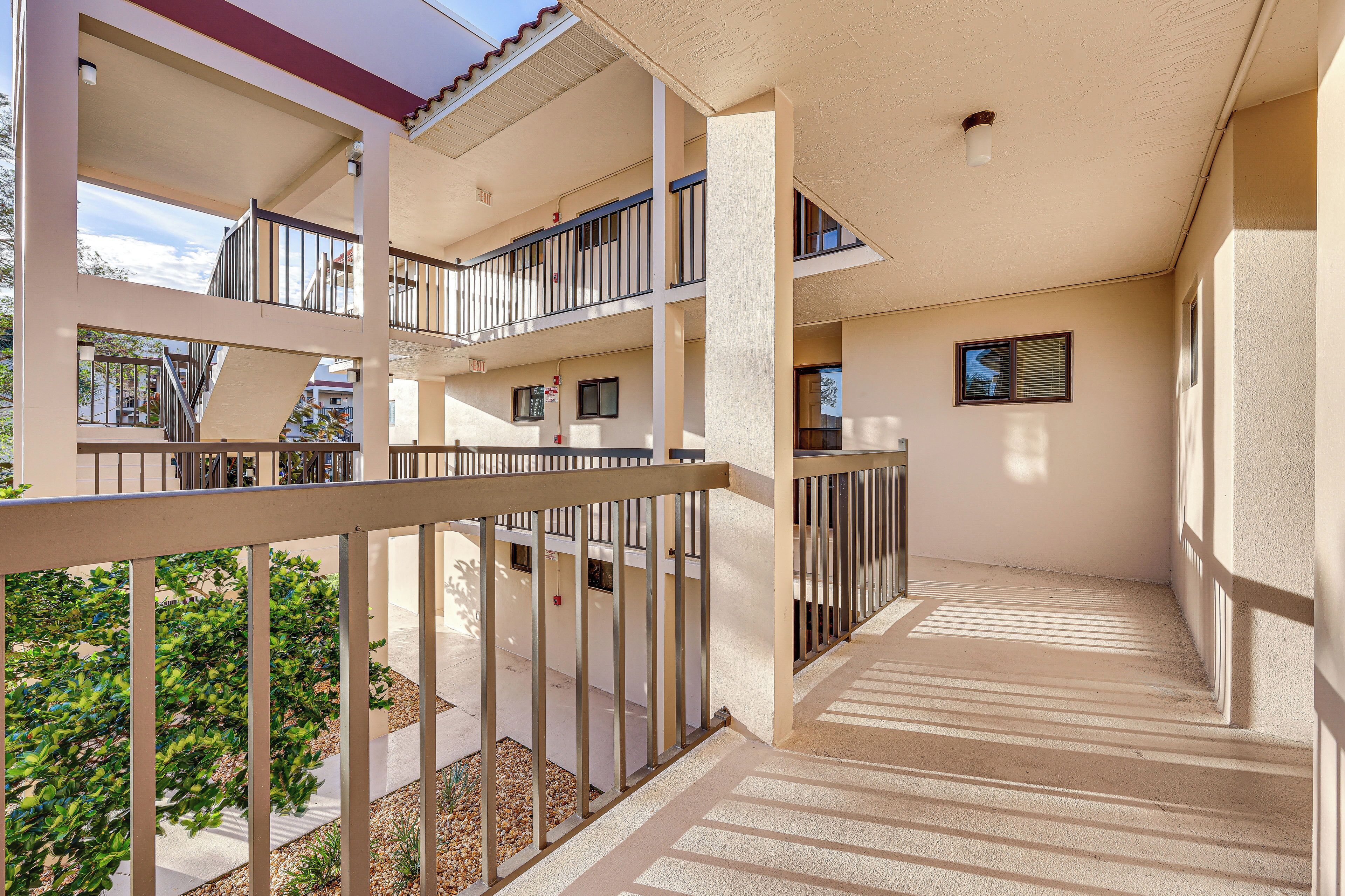 A multi-level residential building with balconies, a covered walkway, and a view of the surrounding area.