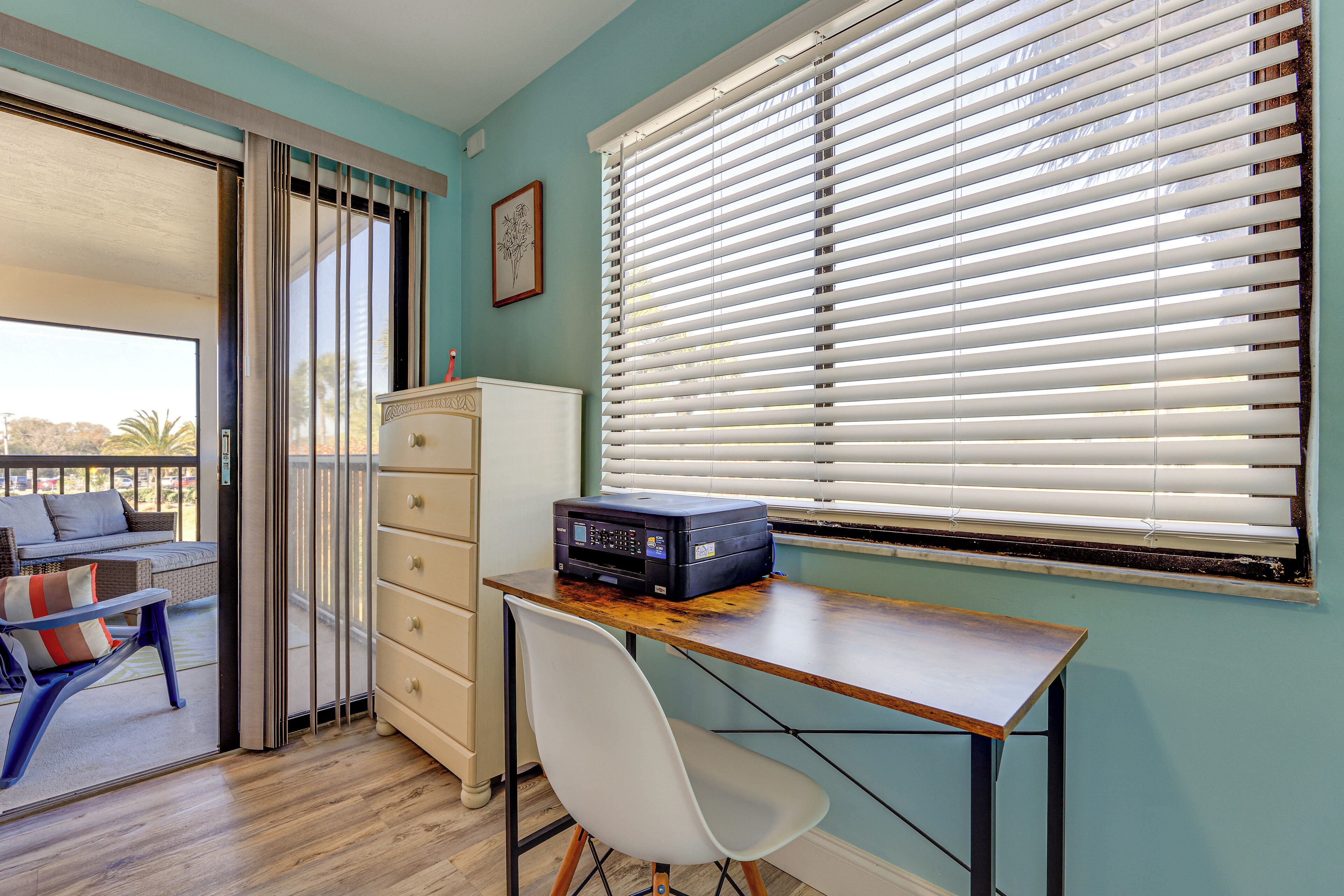 A room with a desk, chair, and a window with blinds.