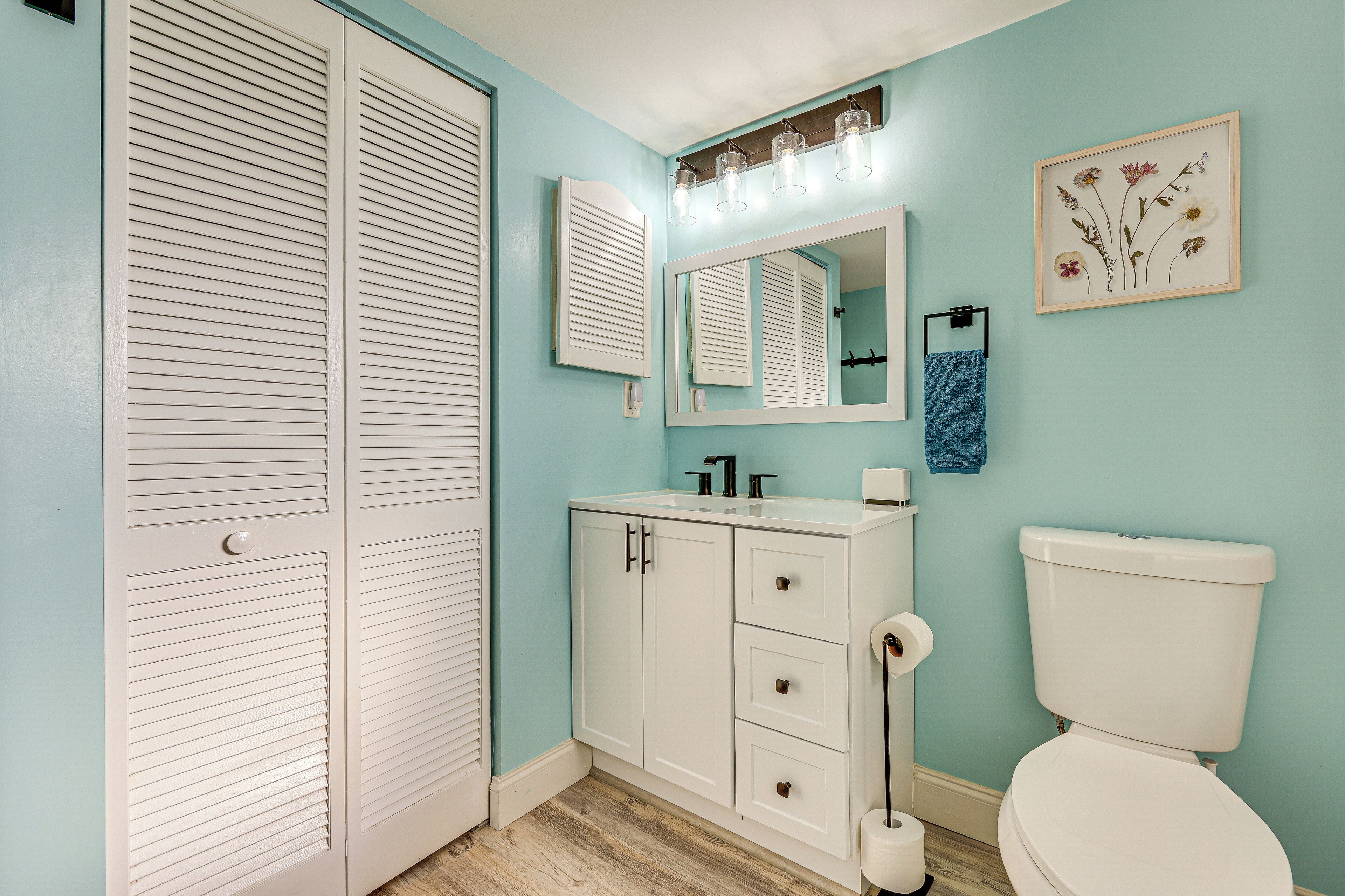 A bathroom with a white vanity, a toilet, and a mirror above the sink.