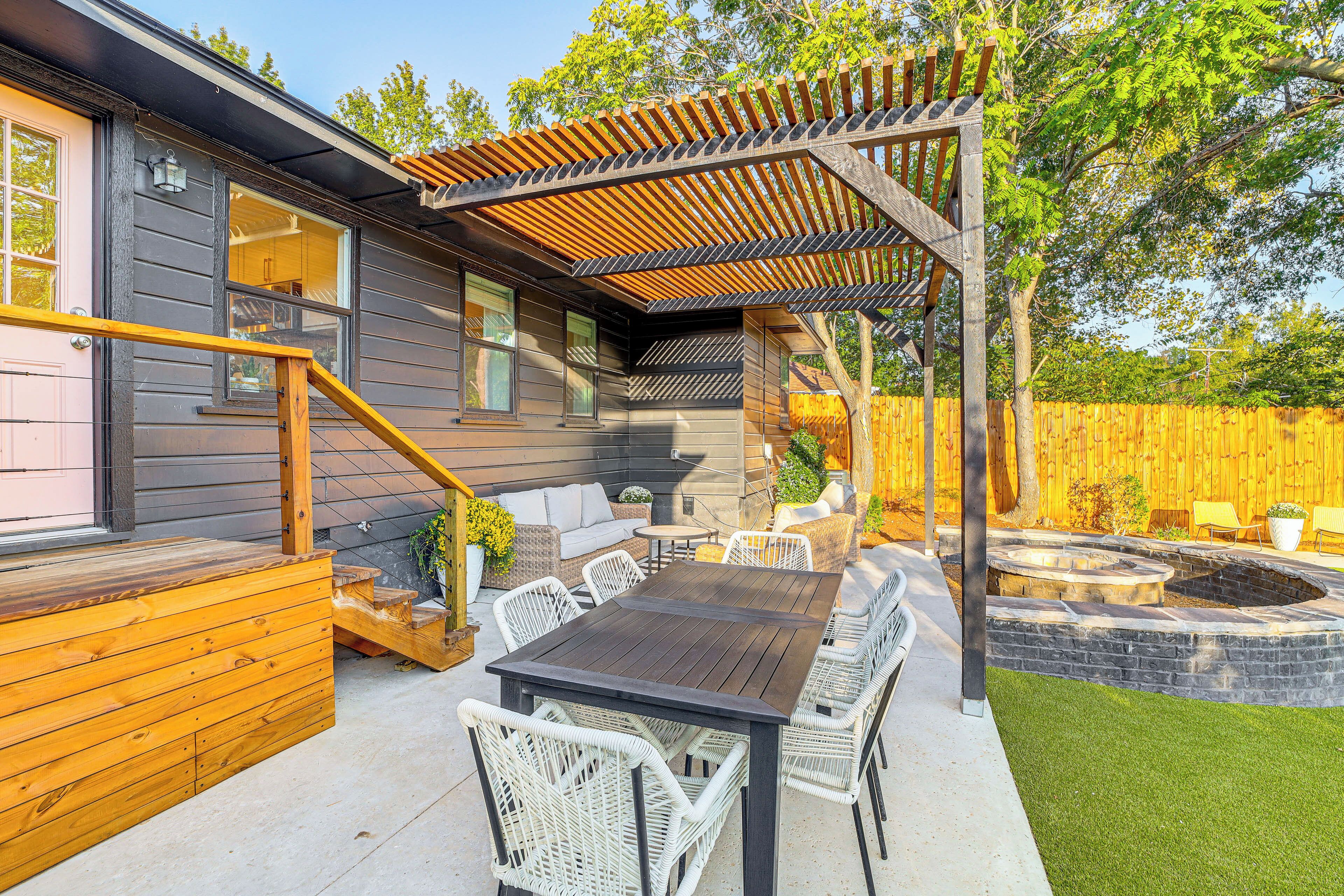A patio with a wooden deck, outdoor seating, and a fire pit.