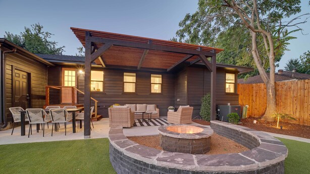 A backyard with a stone fire pit, outdoor furniture, and a covered patio area. - Tulsa Retreat w/ Backyard Oasis & Putting Green! (Tulsa)