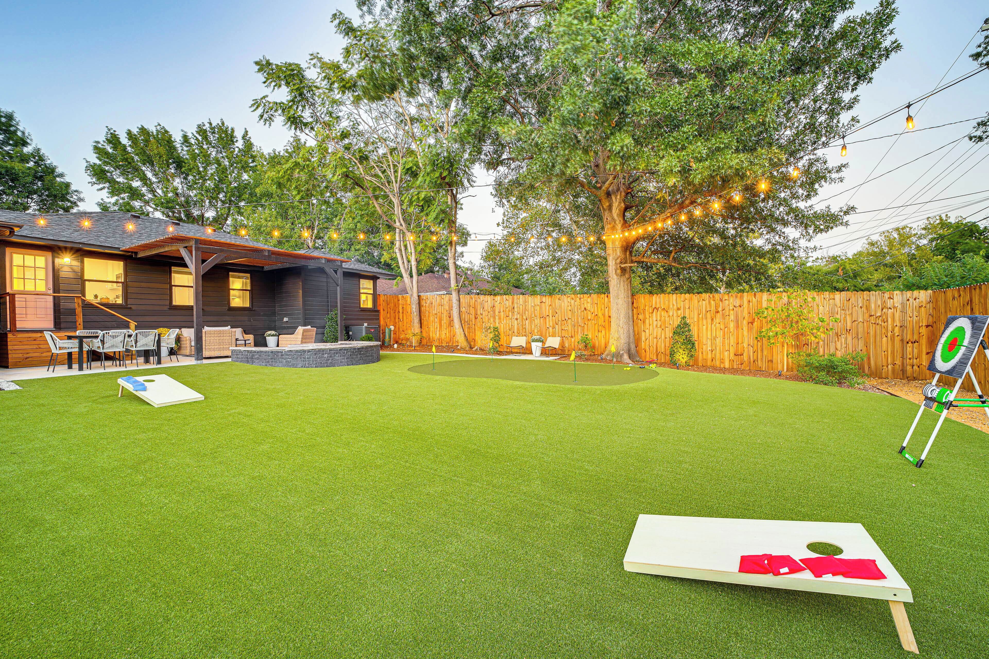 Un jardin avec une pelouse artificielle, une terrasse en bois et une cible pour s’entraîner au tir.