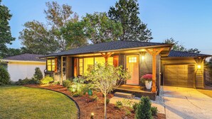 A two-story house with a front porch, a garage, and a well-maintained lawn. - Tulsa Retreat w/ Backyard Oasis & Putting Green! (Tulsa)
