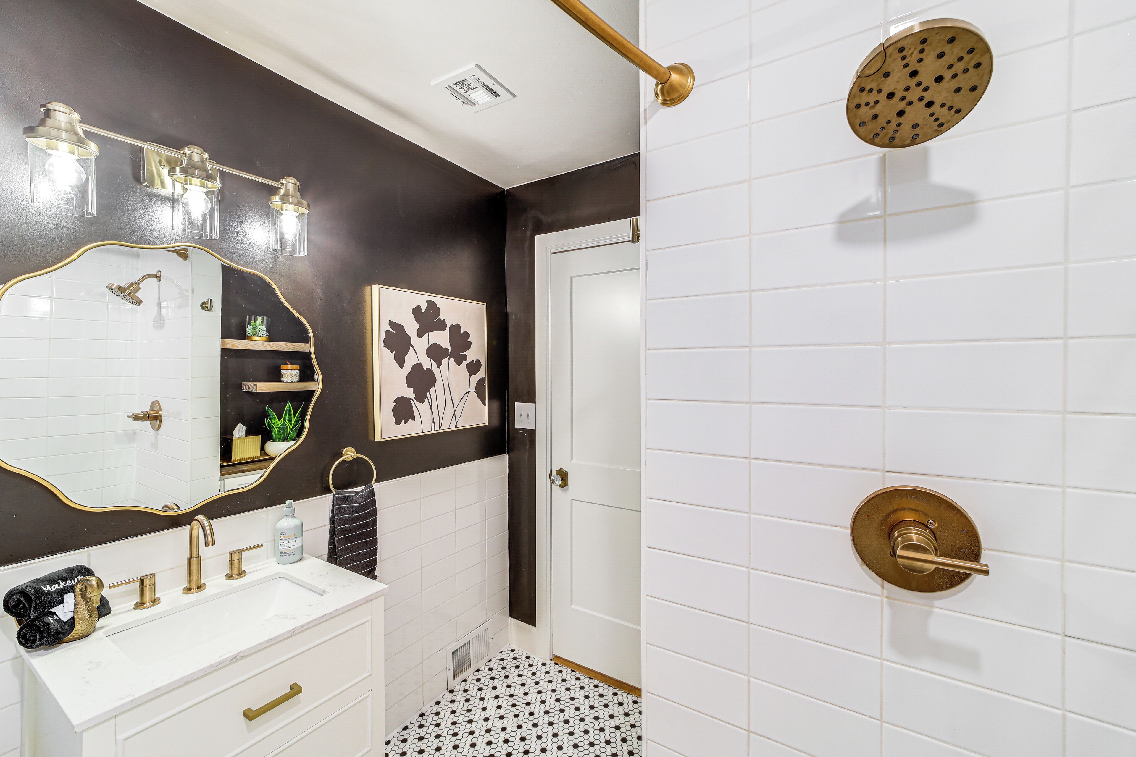 A bathroom with a white sink, gold fixtures, a mirror, and a shower with a gold showerhead.