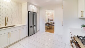 A modern kitchen with white cabinetry, stainless steel appliances, and a tiled floor. - Tulsa Retreat w/ Backyard Oasis & Putting Green! (Tulsa)