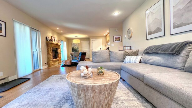 A living room with a grey sofa, a round wooden coffee table, and a fireplace. - Spacious 2 Bdrm, Short walk to lifts! Perfect for a Family! (Mount Crested Butte)