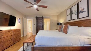 A bedroom with a wooden bed, a ceiling fan, a TV, a dresser, and framed artwork on the wall. - Spacious 2 Bdrm, Short walk to lifts! Perfect for a Family! (Mount Crested Butte)
