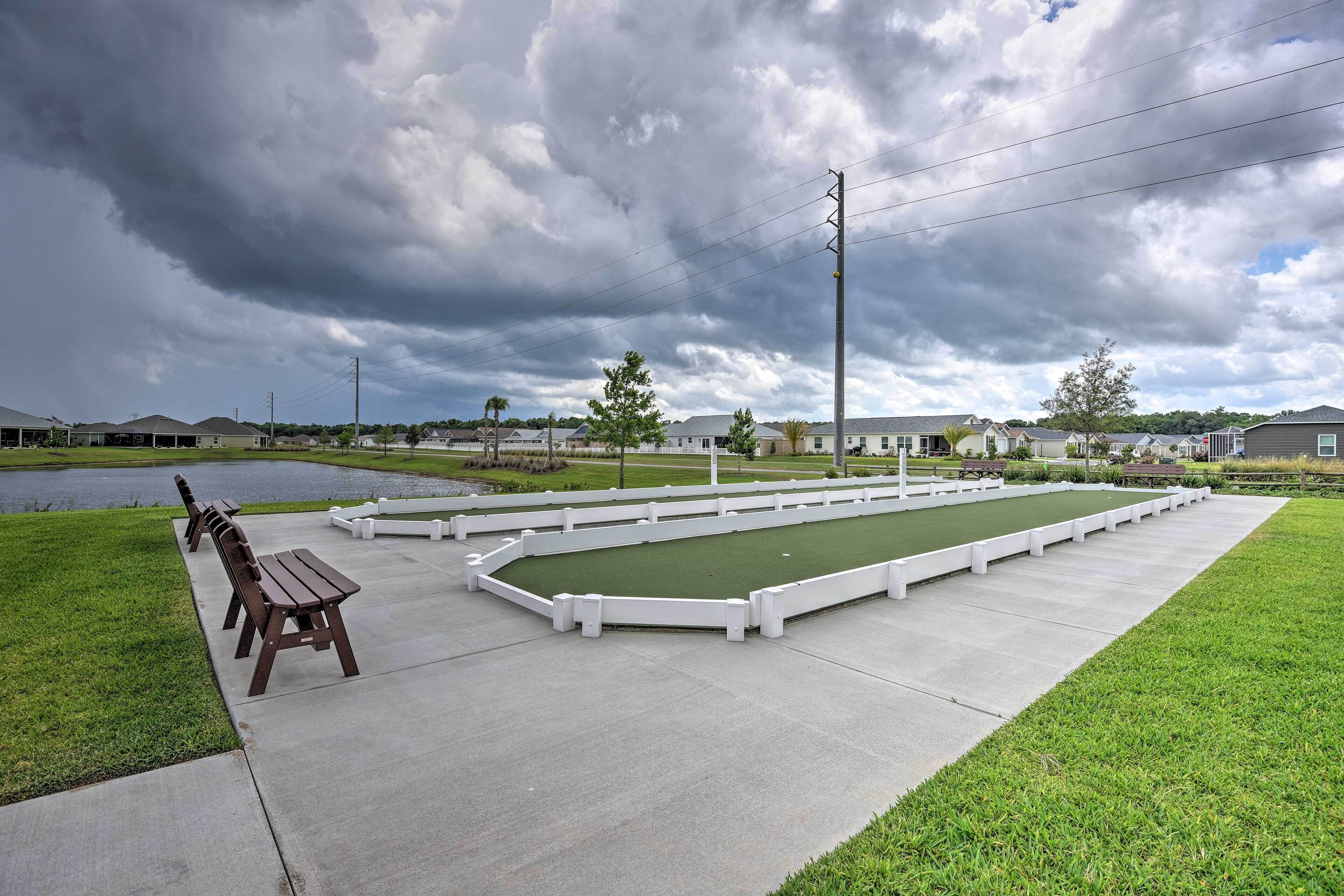 A croquet field with benches and a pond in the background.