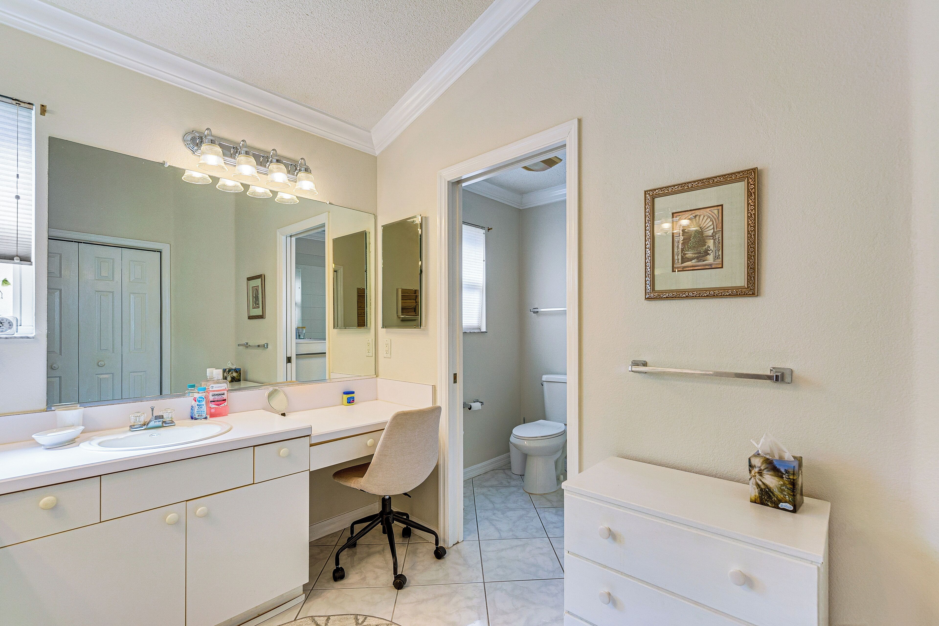 A bathroom with a white vanity, a large mirror, and a framed picture on the wall.