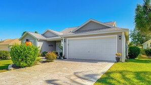 Ein zweistöckiges Haus mit Garage, gepflasterter Auffahrt und gepflegten Rasenflächen.