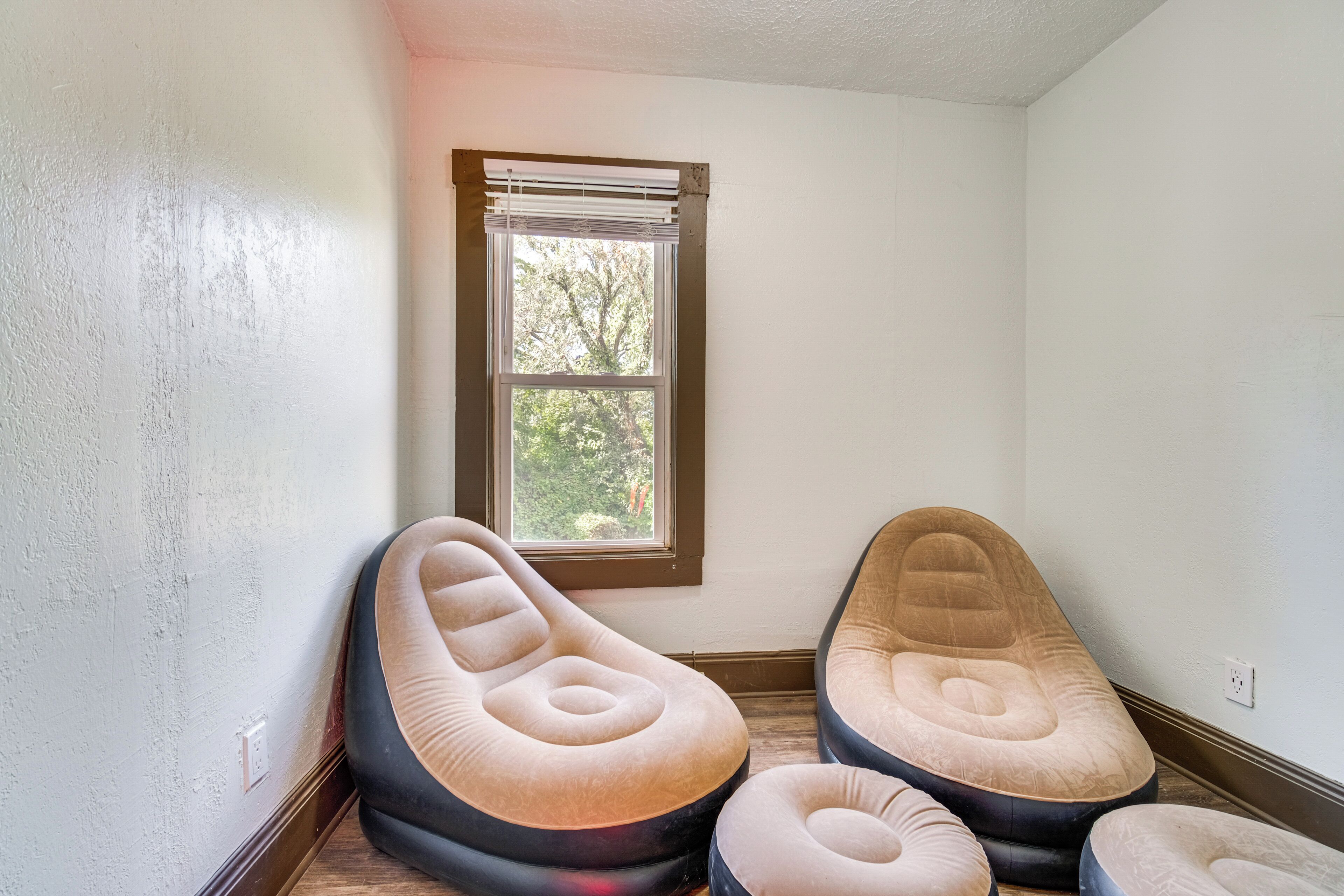 Ein Zimmer mit drei Sitzsäcken, einem Fenster mit Jalousien und einer weißen Wand.