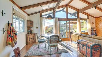 A dining area with a wooden table and chairs, a large window, and a view of the outdoors.