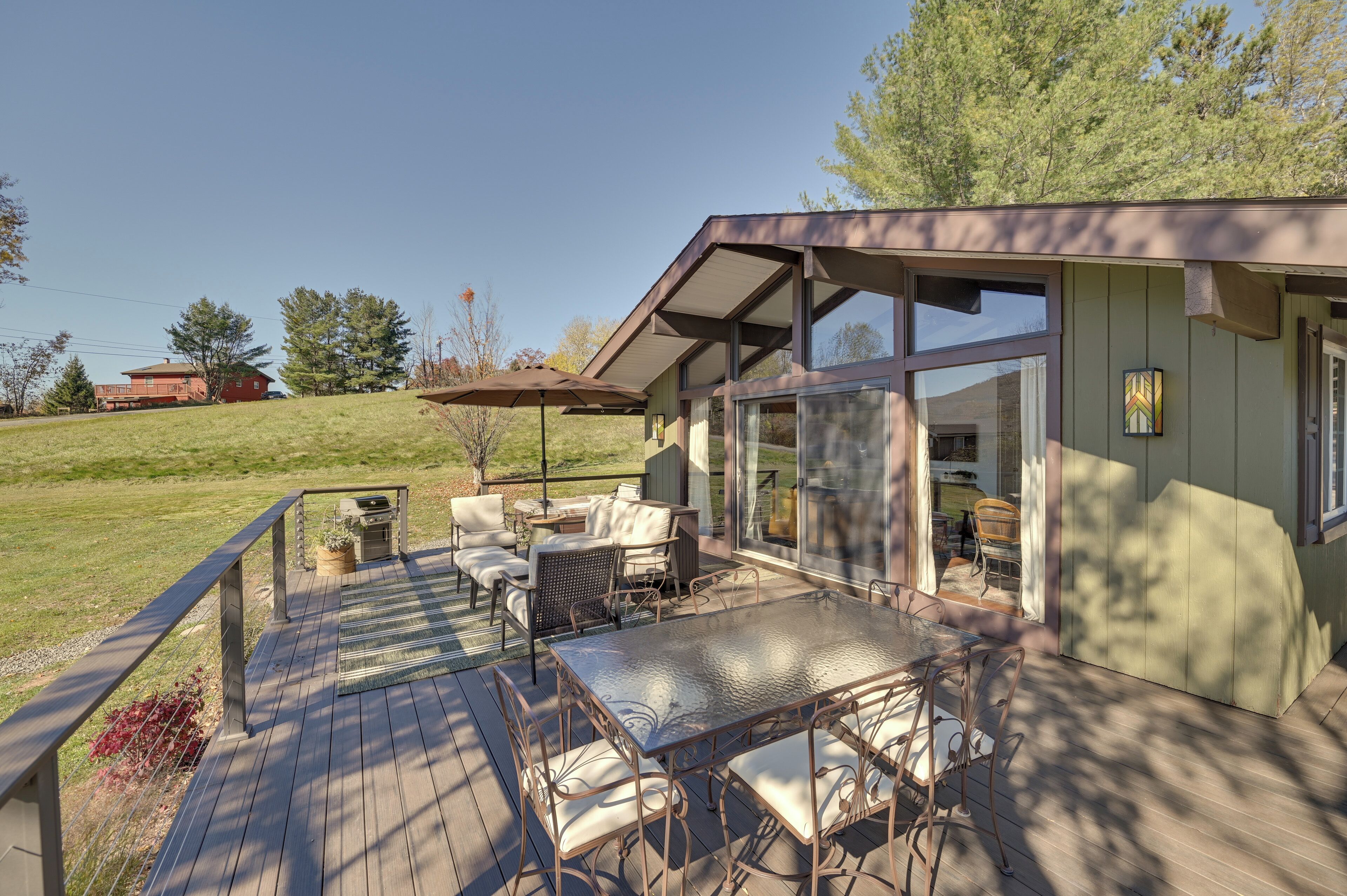 Una terraza con mobiliario exterior y un área de patio con cerramiento de vidrio.