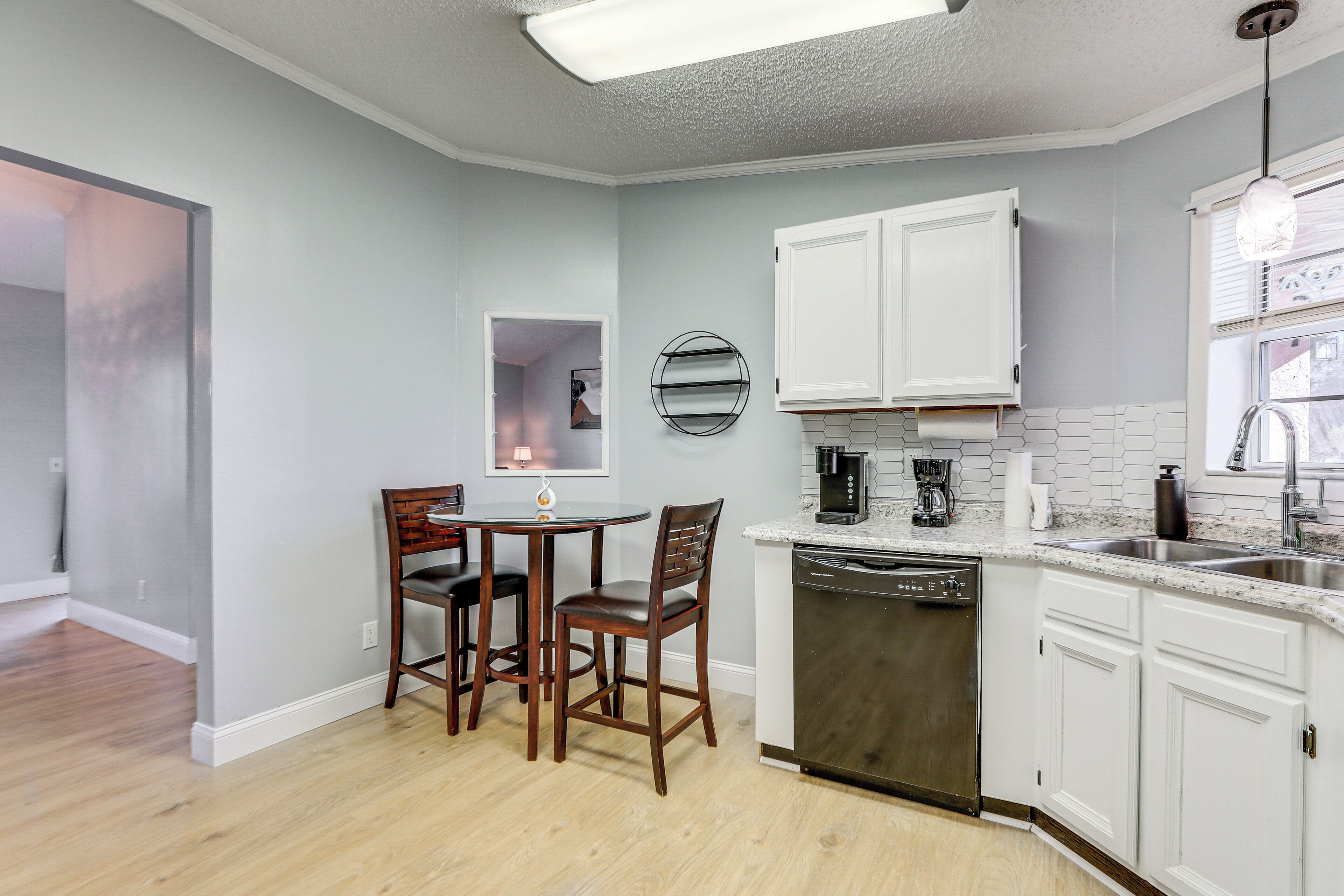 A kitchen with white cabinets, a dishwasher, a coffee maker, and a sink.