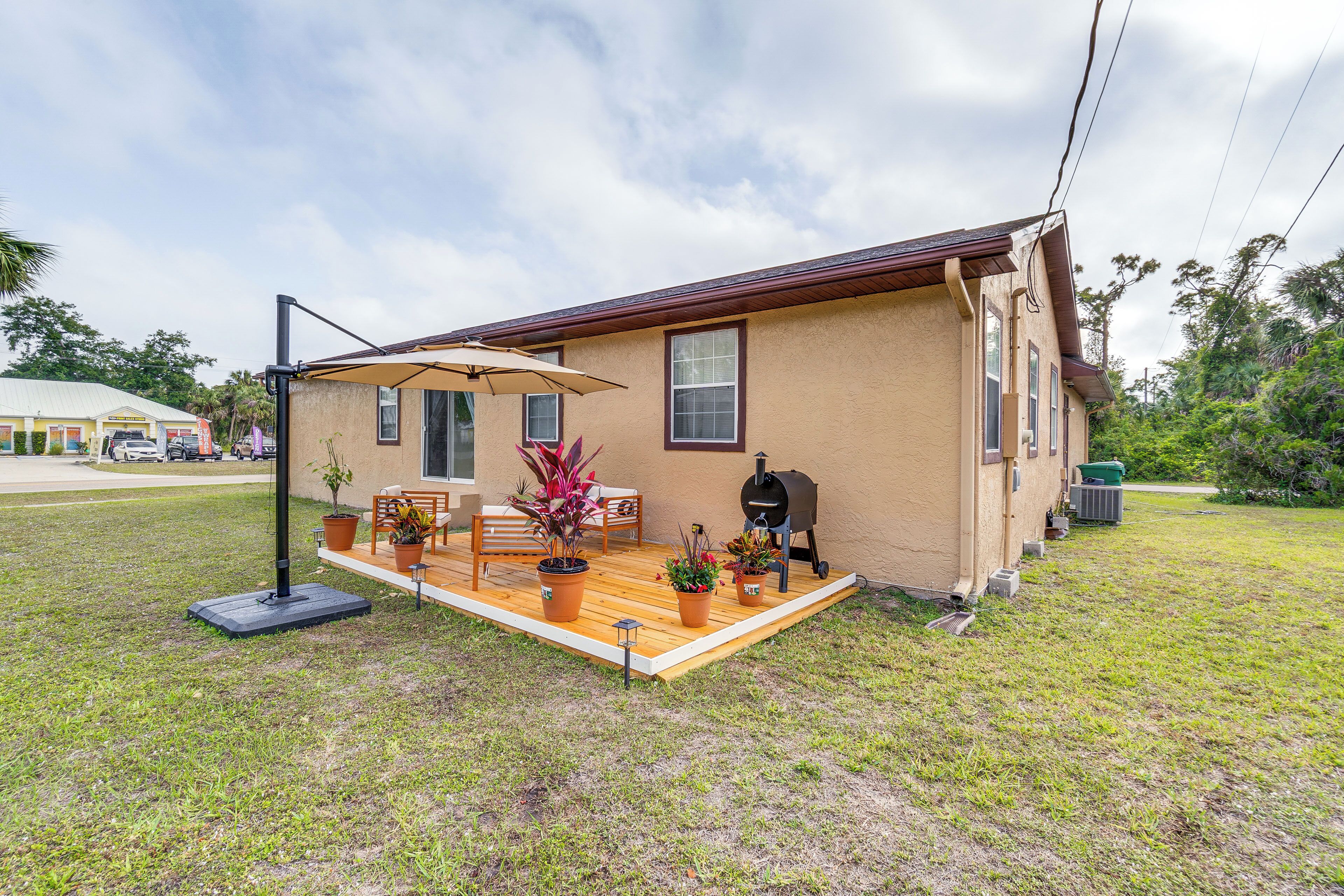 Une petite maison avec un patio, un barbecue et des plantes en pot.