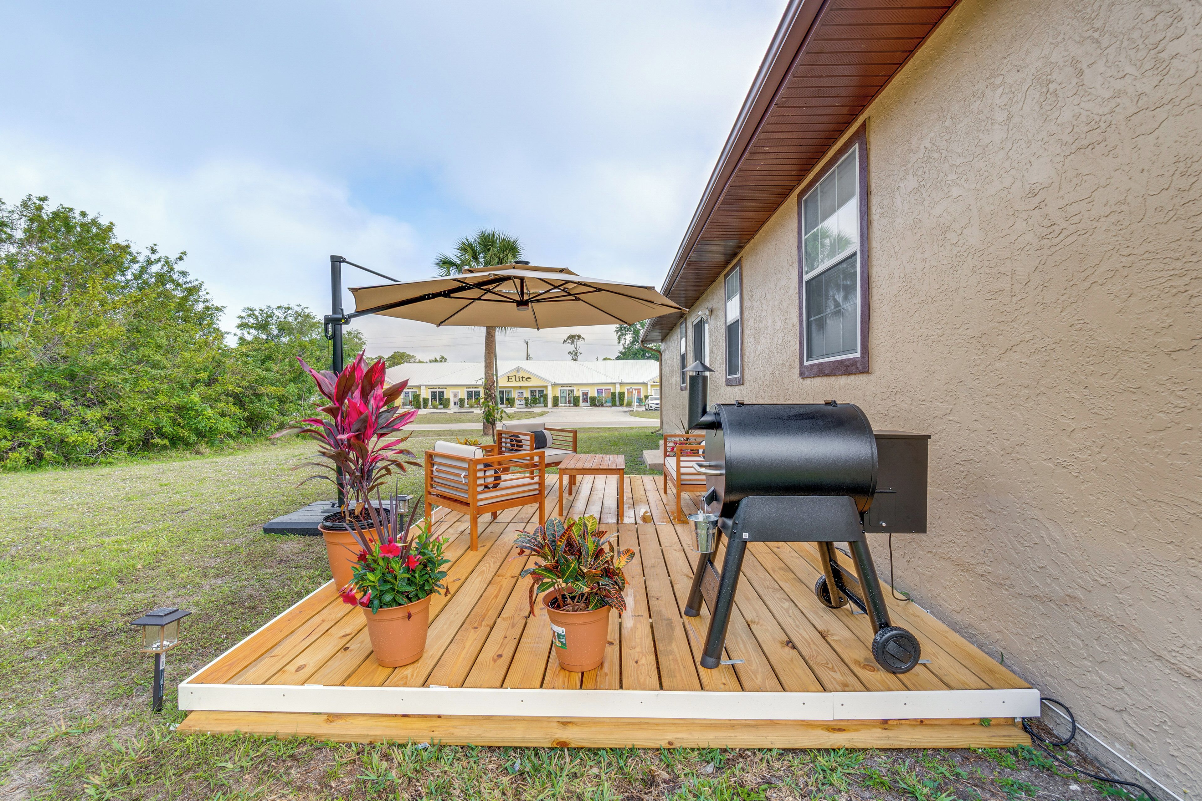 A wooden deck with outdoor furniture, a grill, and potted plants.