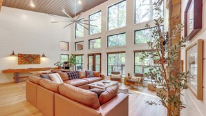 A spacious living room with a large sectional sofa, a dining table, and a ceiling fan. - Cozy Secluded Cabin in the Heart of Hochatown (Broken Bow)