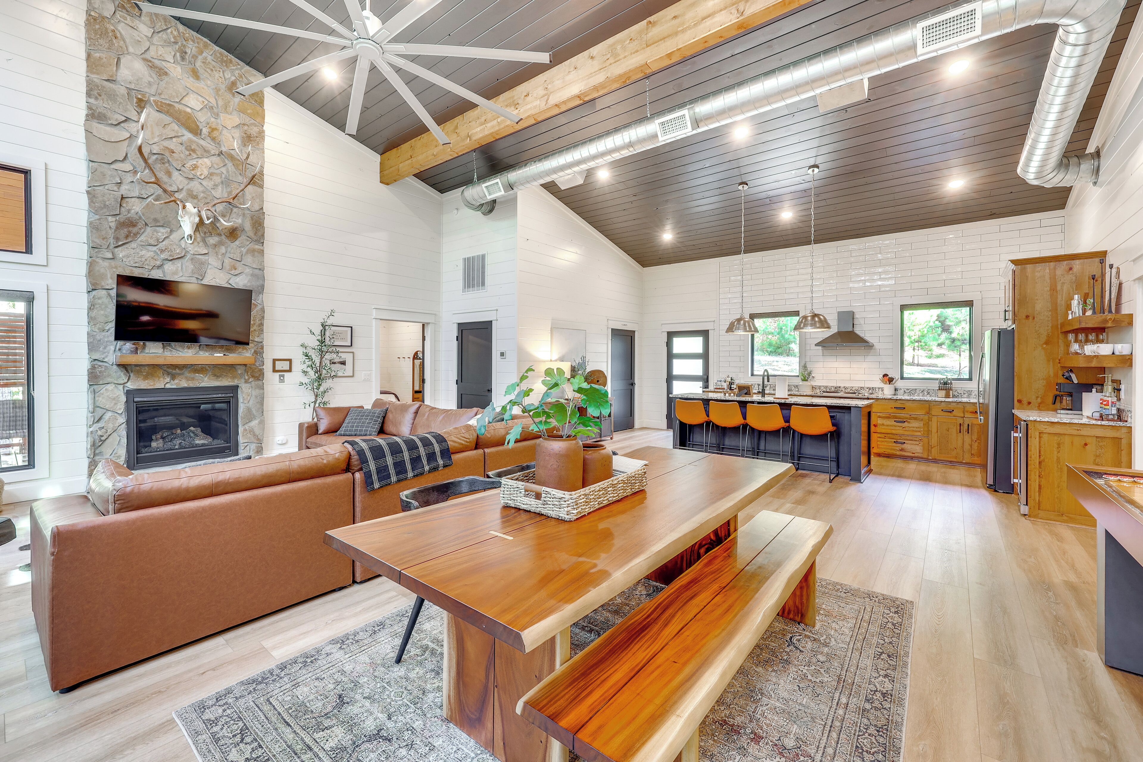 A spacious living area with a stone fireplace, a wooden dining table, and a cozy seating arrangement.