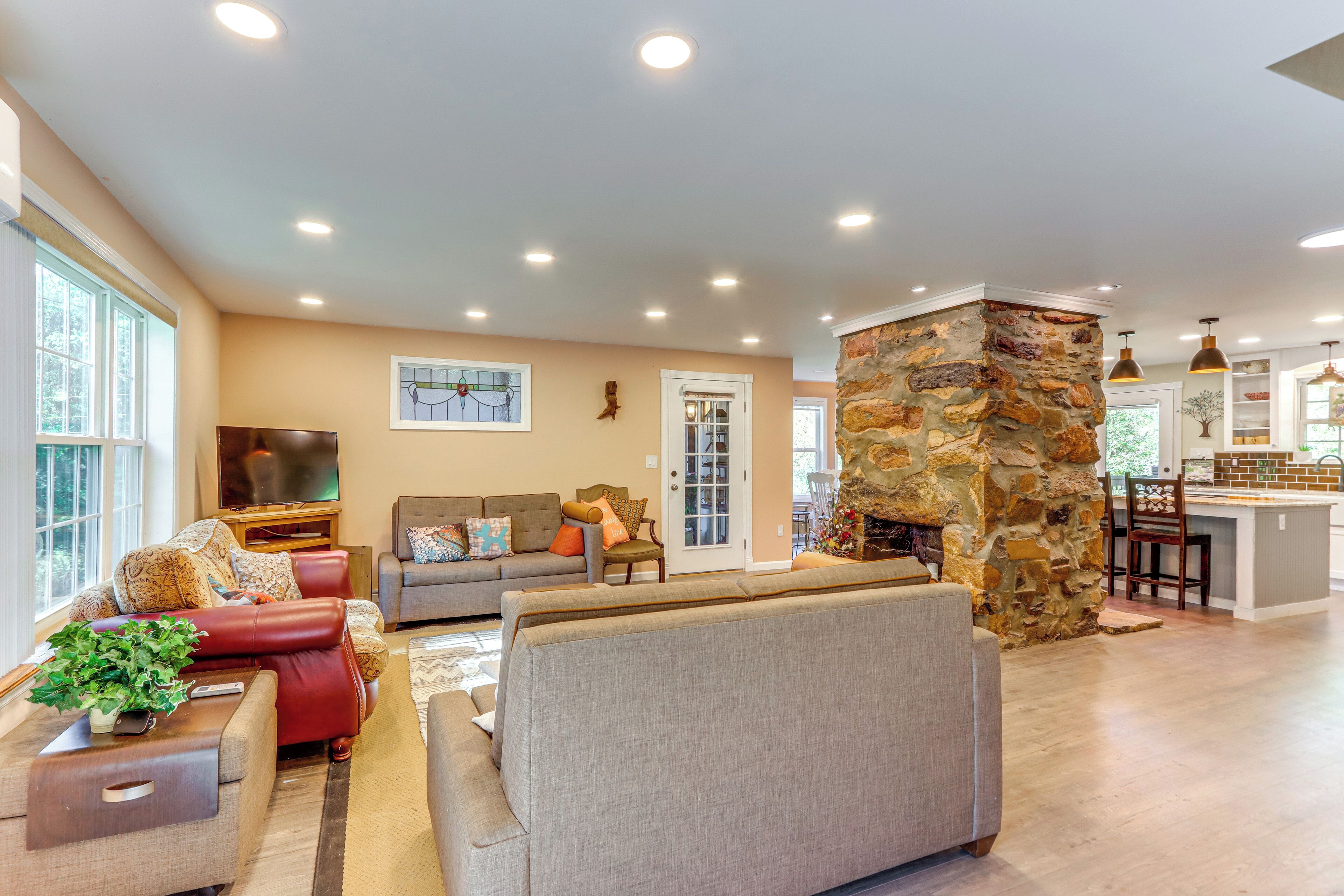 A spacious living room with a stone fireplace, a large sofa, and a television.