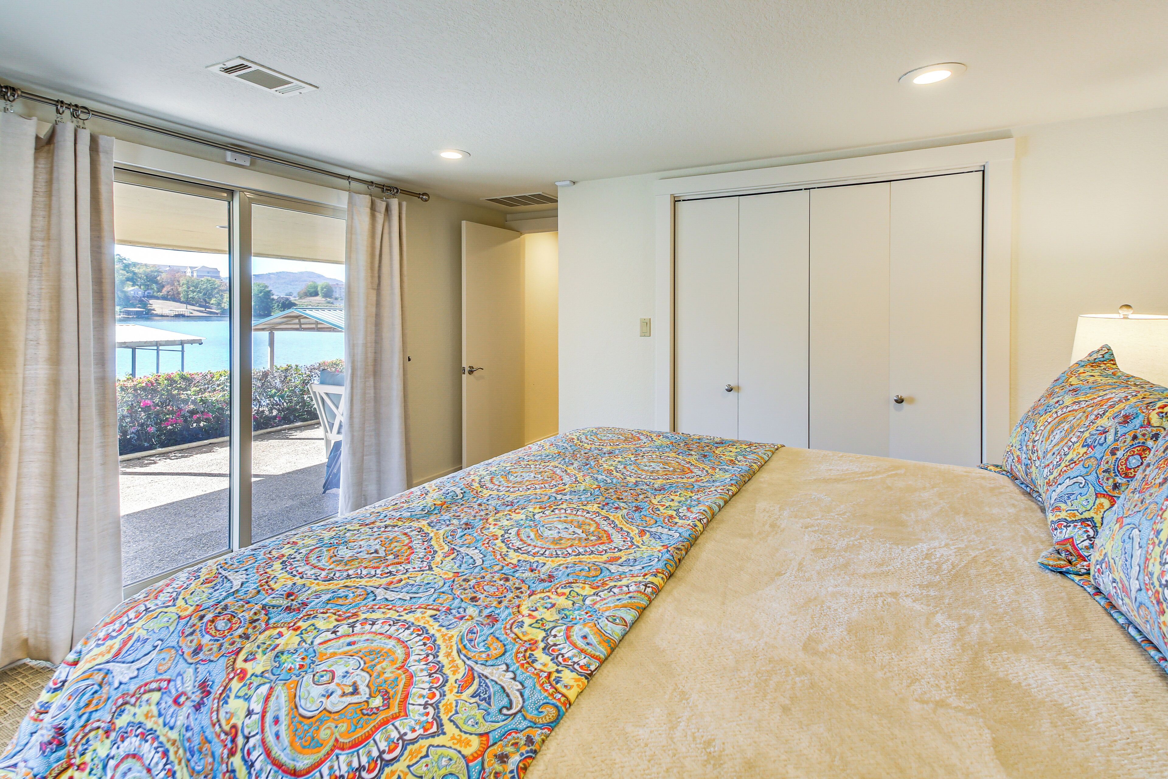 A bedroom with a large bed, a sliding glass door to a balcony, and a wardrobe.