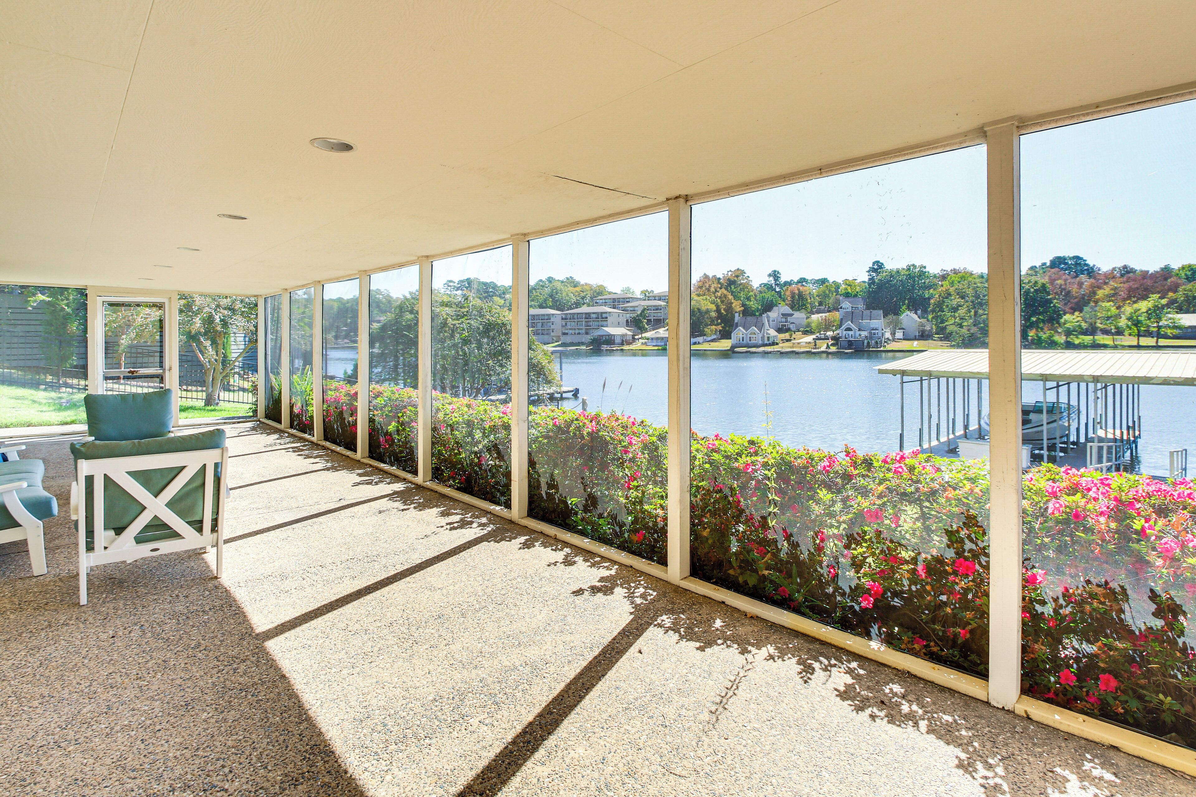A covered outdoor area with a view of a lake, seating, and a railing.