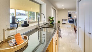 A modern kitchen with a large window, a built-in sink, and a countertop with a bowl and cloth.