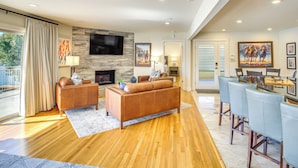 A spacious living room with a stone fireplace, leather sofas, a flat-screen TV, and a bar area with high stools.