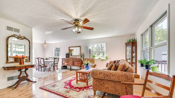 A spacious living room with hardwood floors, a ceiling fan, a patterned sofa, and a dining area with a wooden table and chairs. - Private Deck: Berkeley Springs Getaway! (Berkeley Springs)