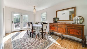A dining area with a table and chairs, a wooden cabinet, and a large mirror on the wall. - Private Deck: Berkeley Springs Getaway! (Berkeley Springs)